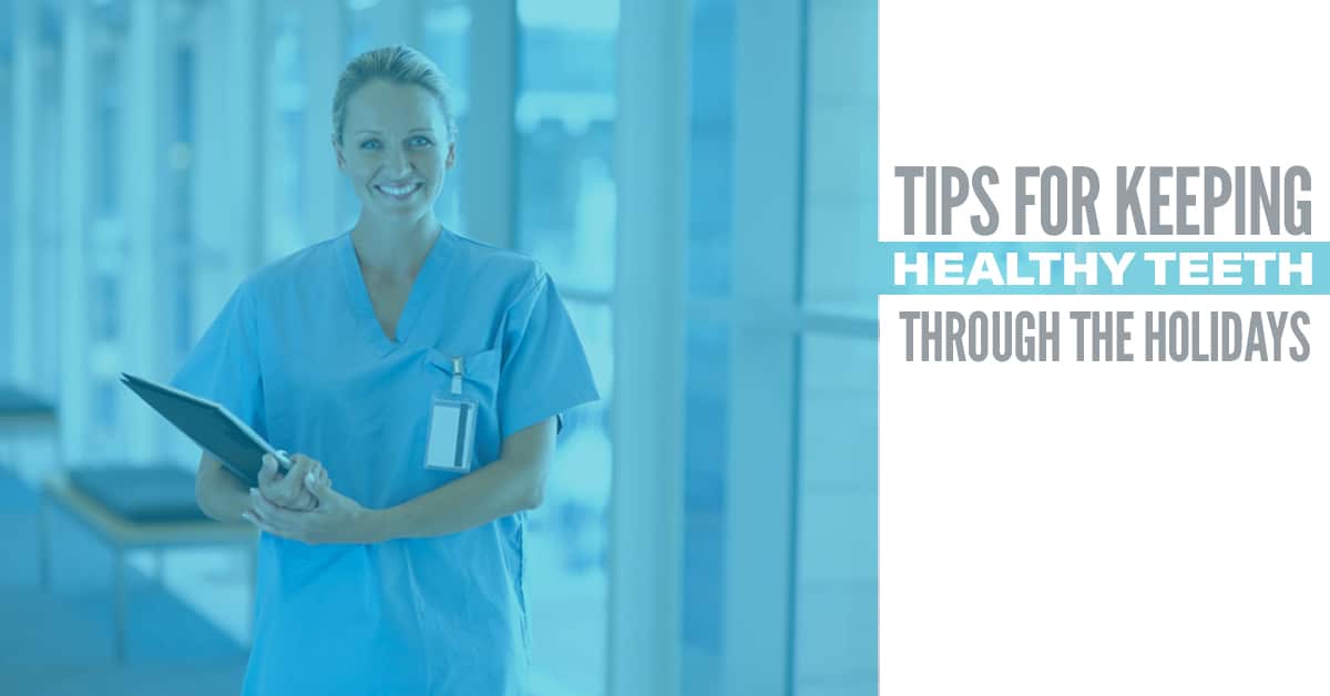 Dentist in scrubs with arms crossed in clinical setting, promoting holiday dental health tips.