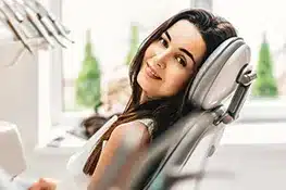 Woman relaxing in dental chair wearing headphones in modern dental office setting.