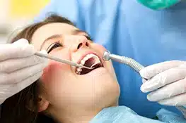 Dental professional examining patient's teeth with tools during routine checkup in clinical setting.