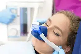 Young patient receiving dental treatment with blue gloved dentist in clinical setting.