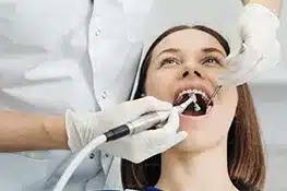 Dental professional performing oral examination on patient using intraoral camera in clinical setting.