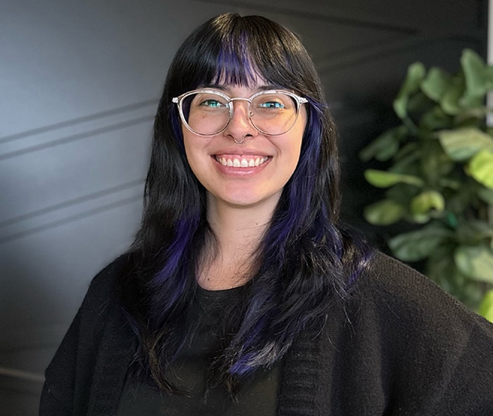Smiling woman wearing glasses and black clothing in a professional dental office setting.