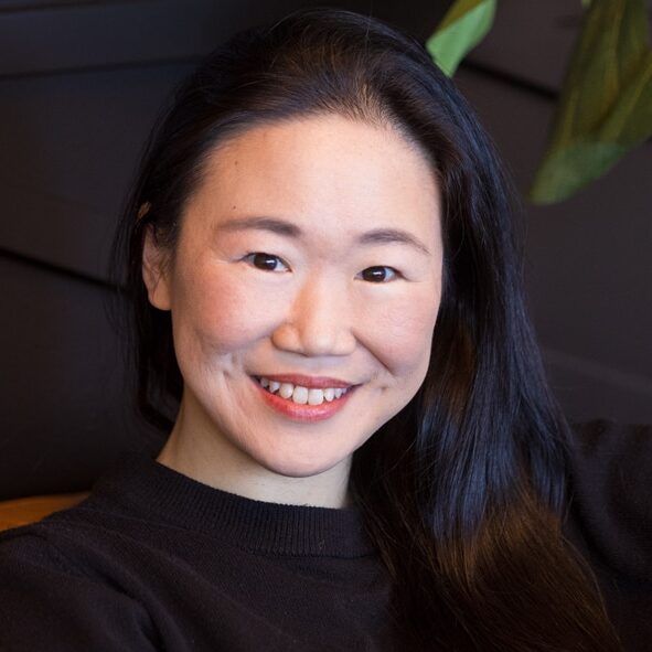 Smiling woman with long dark hair wearing black shirt in indoor setting